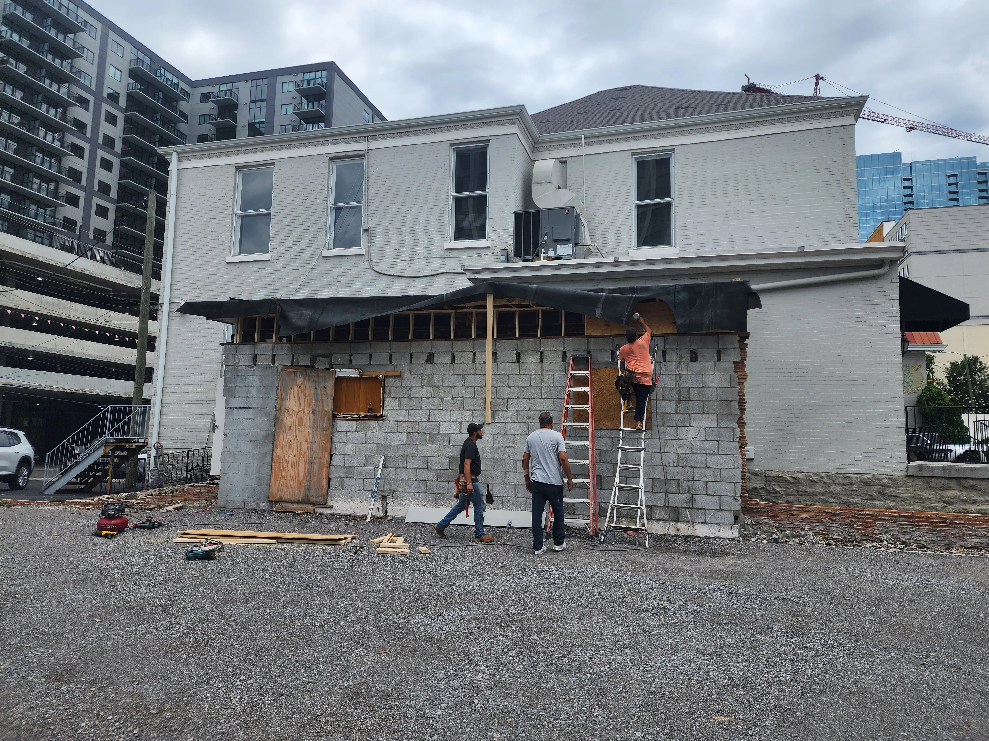 Commercial building storefront renovation with concrete block base, wooden framing, and white painted upper facade
