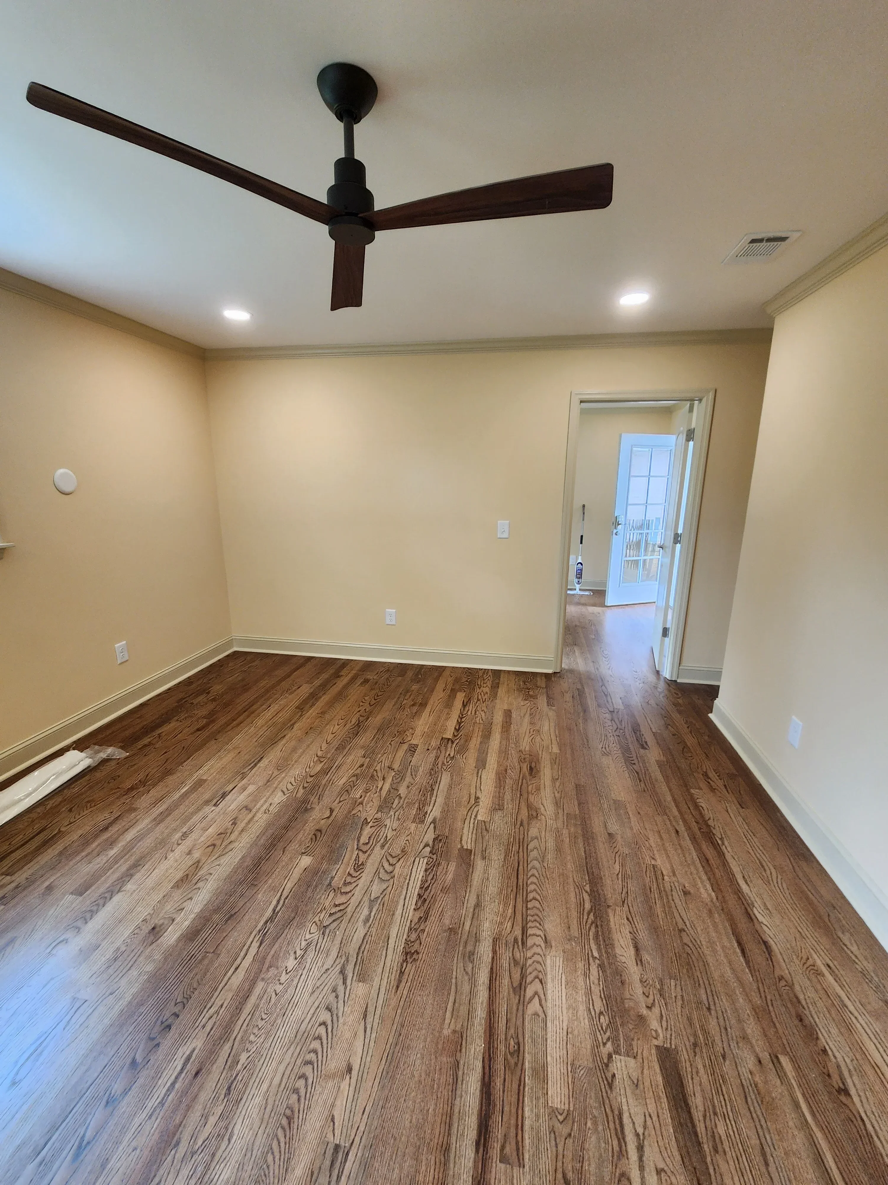 Wood plank accent wall in basement with recessed lighting and ceiling fan installation