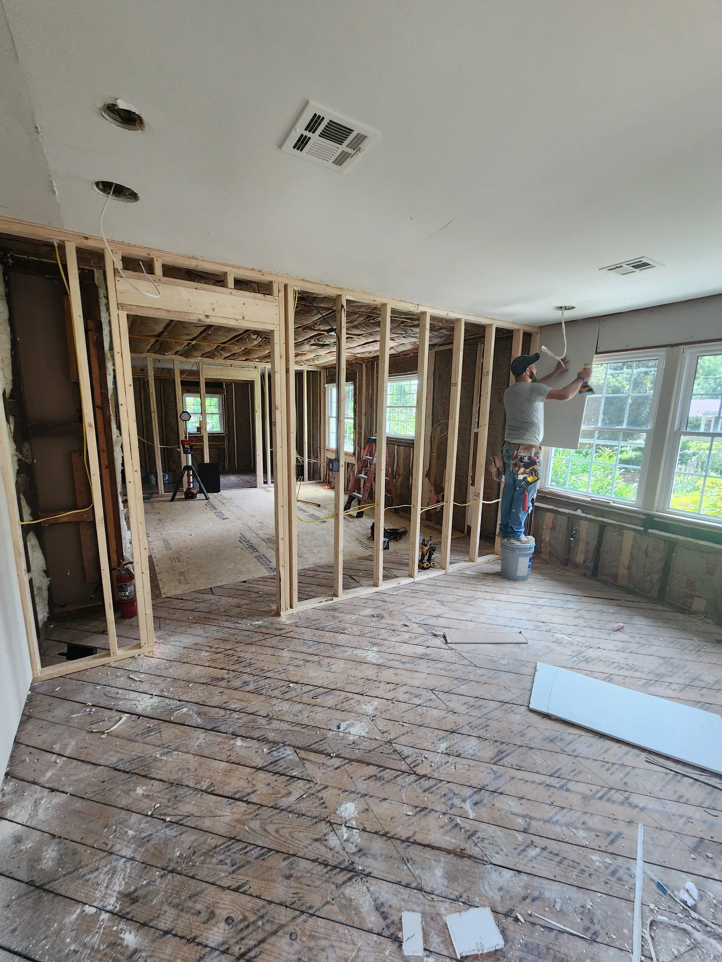 Kitchen framing with new lumber studs, drywall, and exposed subfloor during renovation